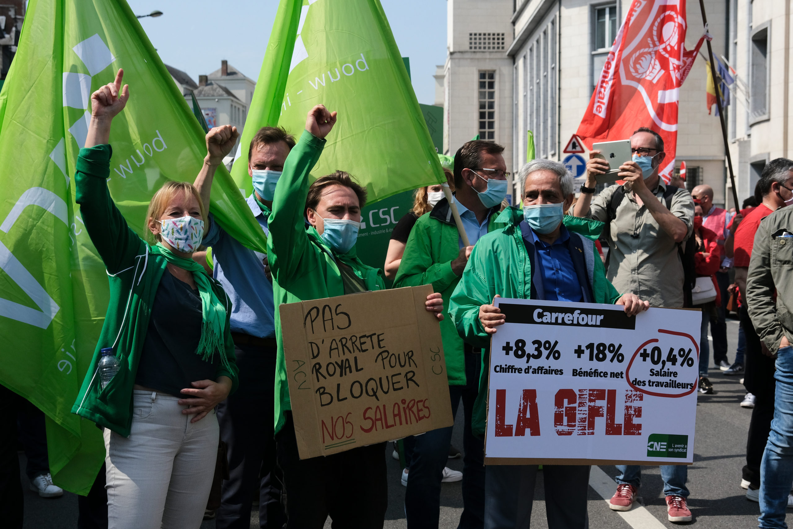 Des manifestants avec des masques portent des drapeaux et des pancartes