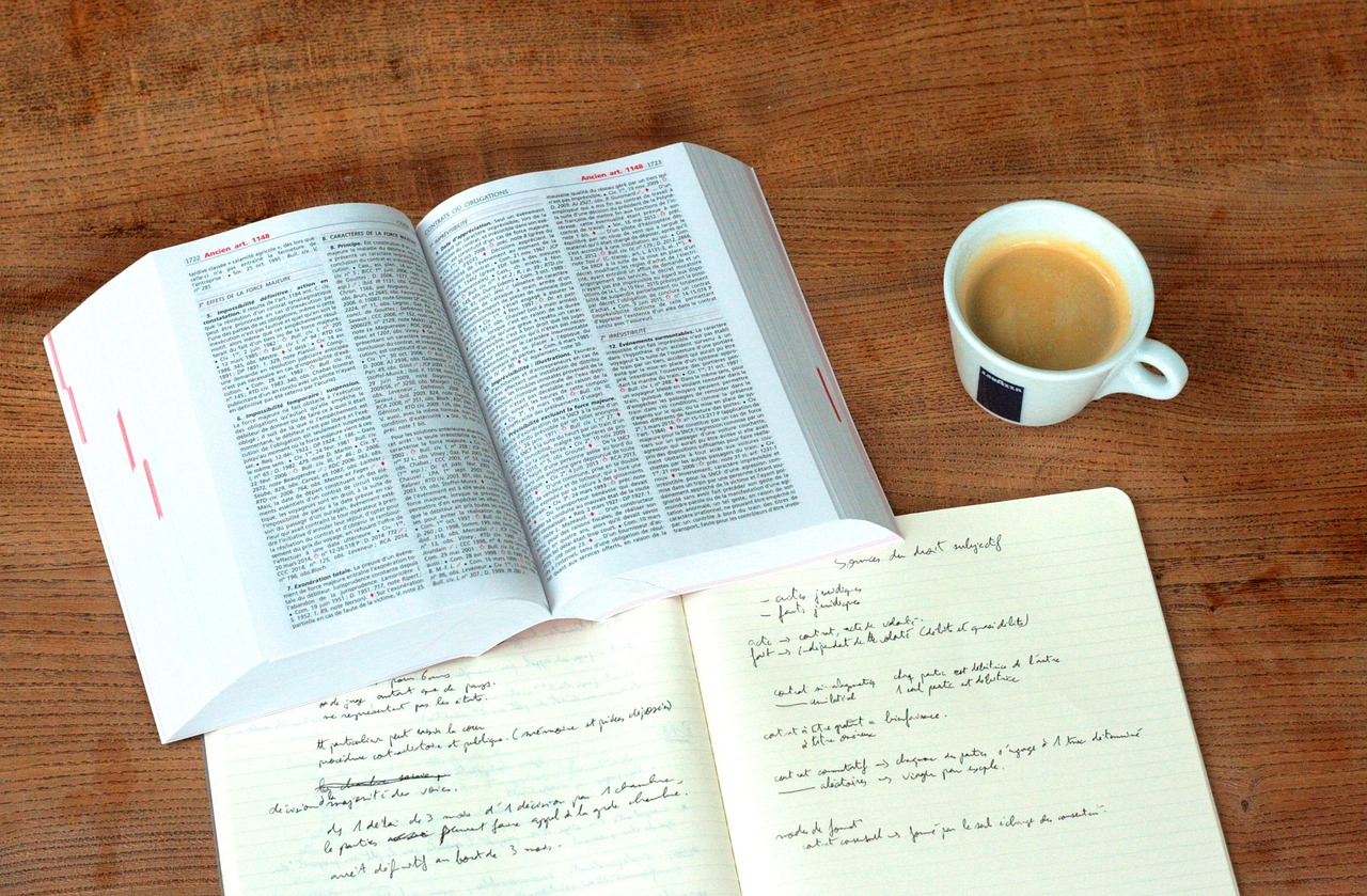 Un livre ouvert avec une tasse de café et un carnet de notes