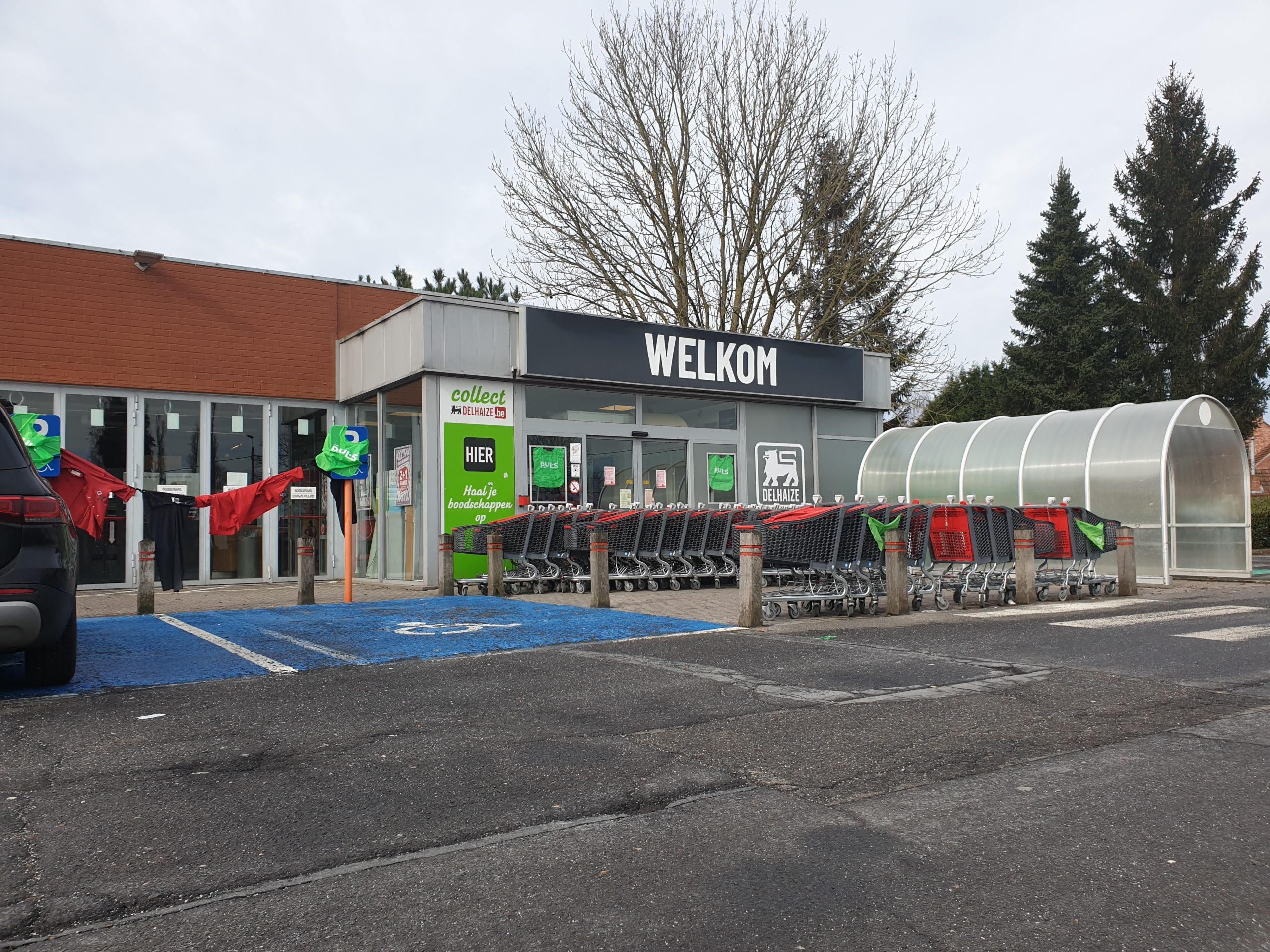 Entrée d'un supermarché avec des caddies rangés à l'extérieur