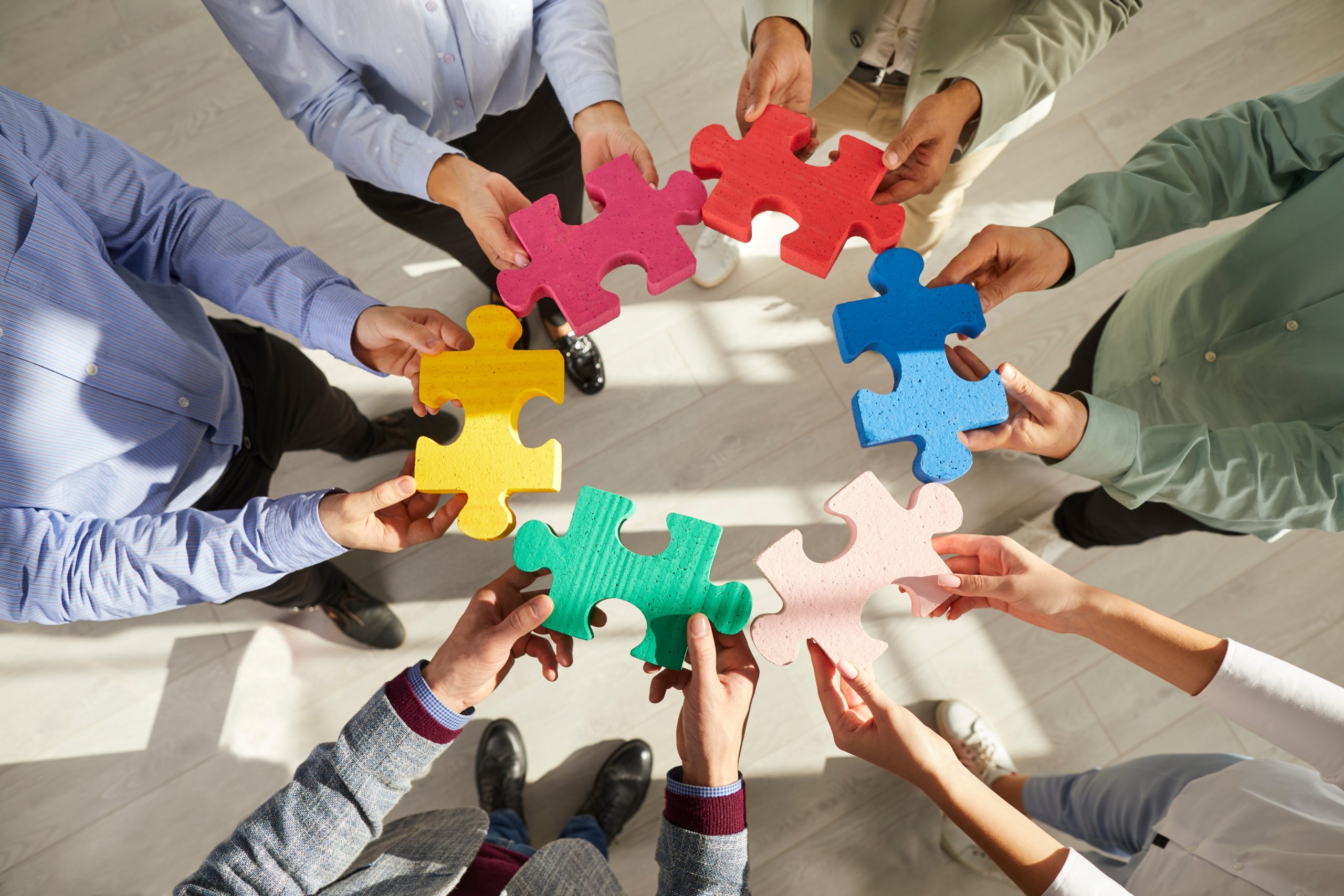 Un groupe de personnes assemblent des pièces de puzzle colorés